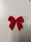 10 pack red satin bow with a self-adhesive back, ready for use in crafting.